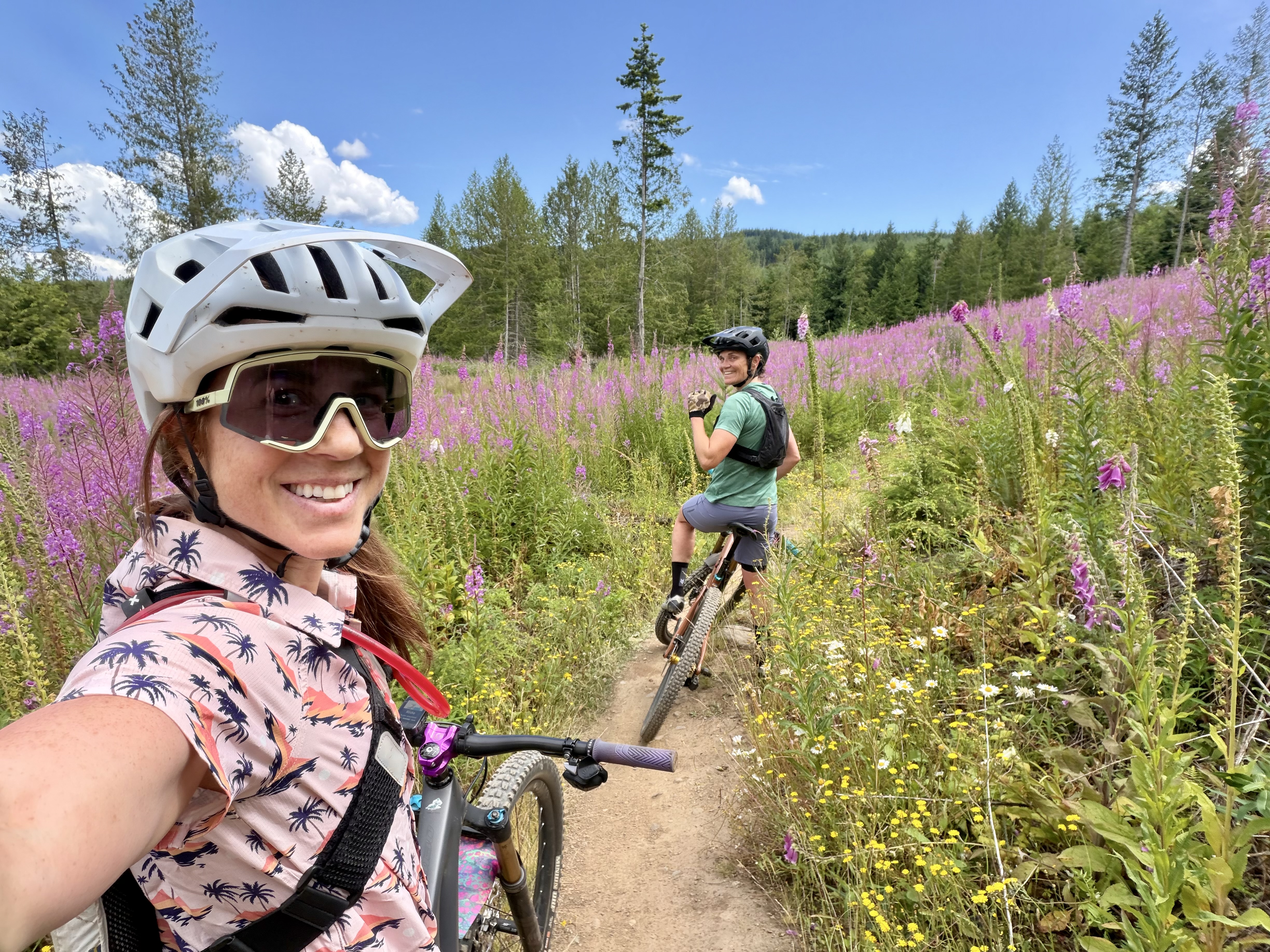Two women mountain biking through a wildflower field