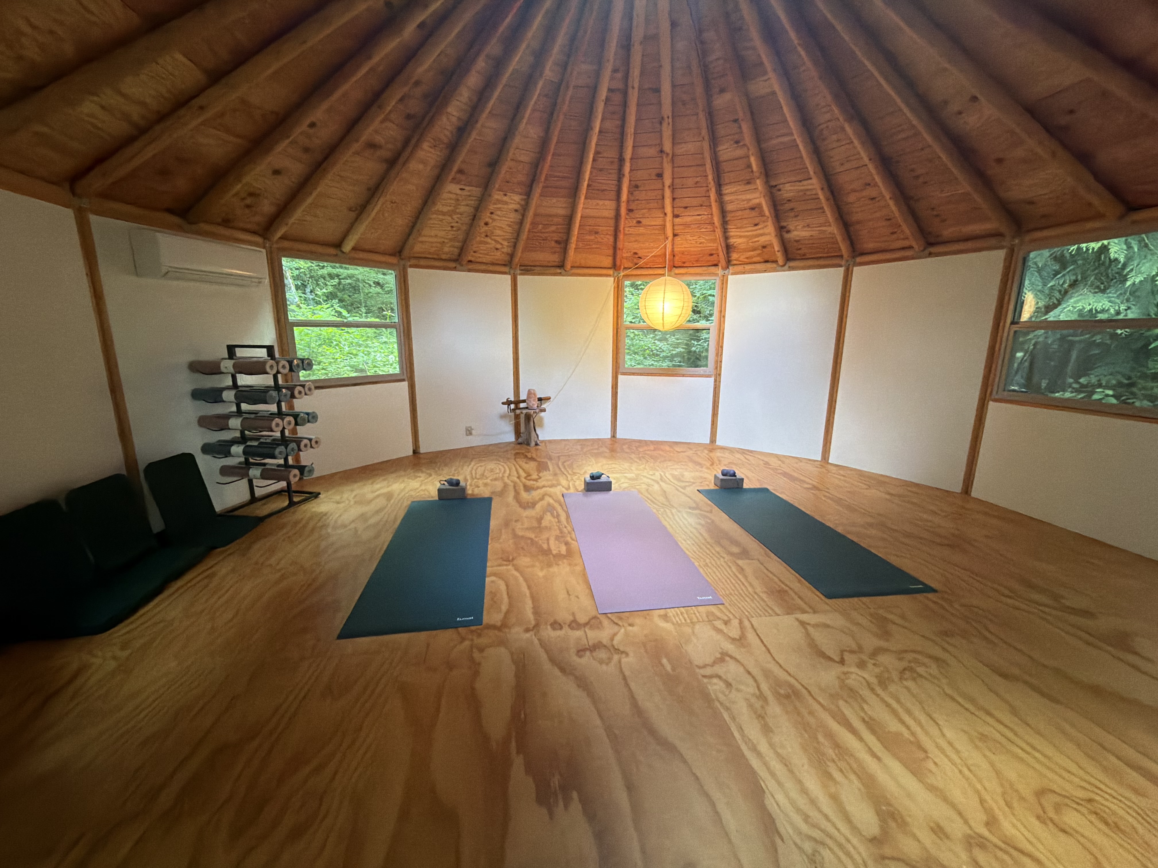 Yurt interior with three yoga mats and paper lantern light